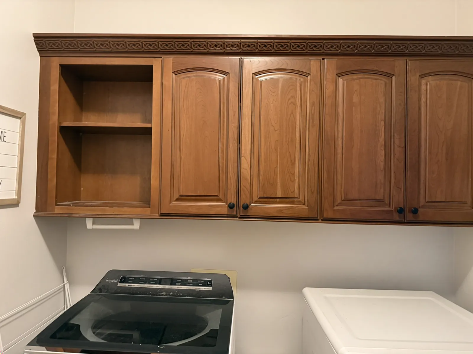 A laundry room with dated honey-wood cabinets, before Valley Painting Pros refinished it.