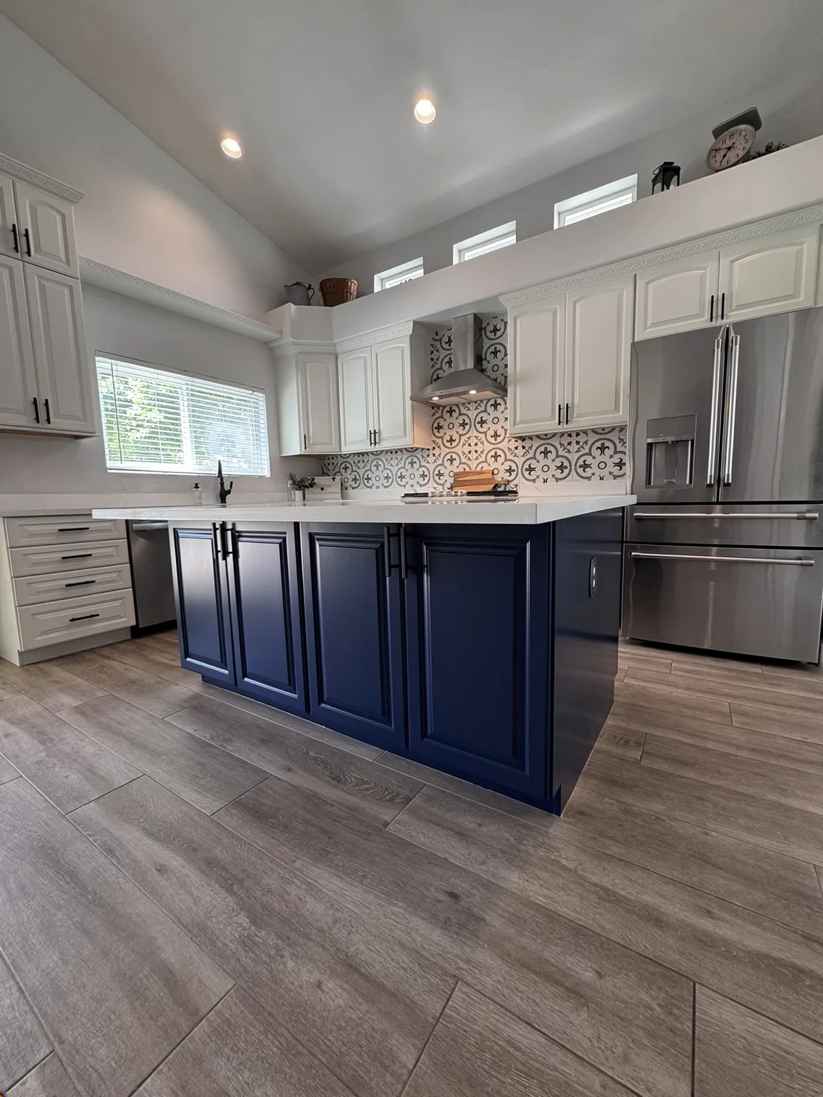A bright white East Valley kitchen with a navy-blue island, cabinets refinished by Valley Painting Pros.