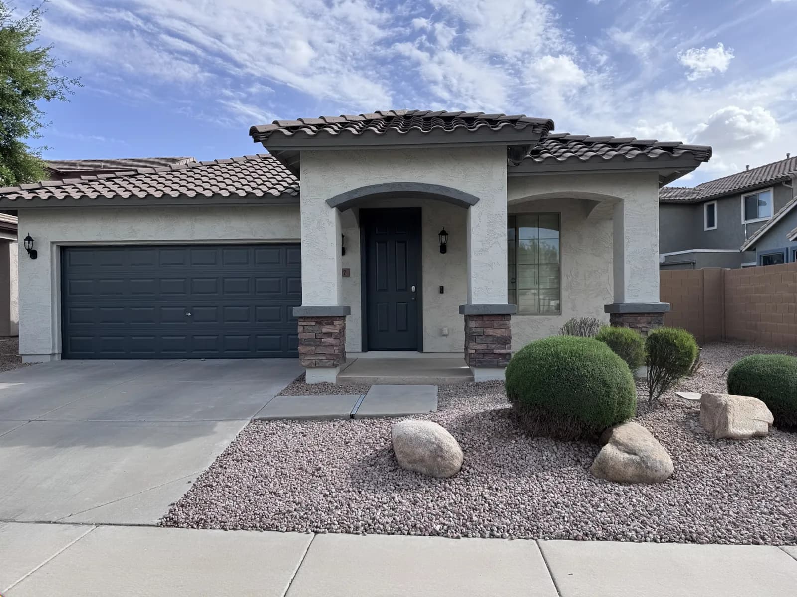 A freshly repainted single-story East Valley home with a crisp navy garage door and clean tan stucco — exterior work by Valley Painting Pros.