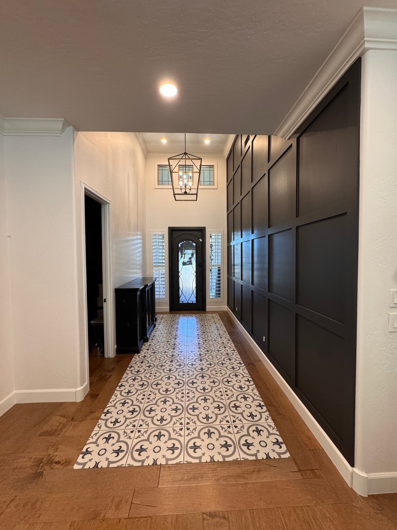 A freshly finished home entryway with a dark navy accent wall, white walls, and warm wood floors — a Valley Painting Pros project.