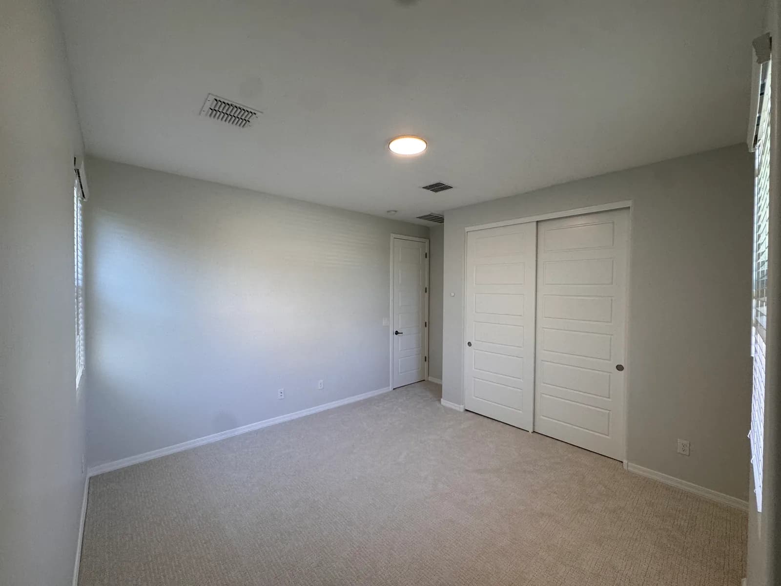 A bedroom with a soft blue accent wall and crisp white closet doors, freshly painted by Valley Painting Pros.