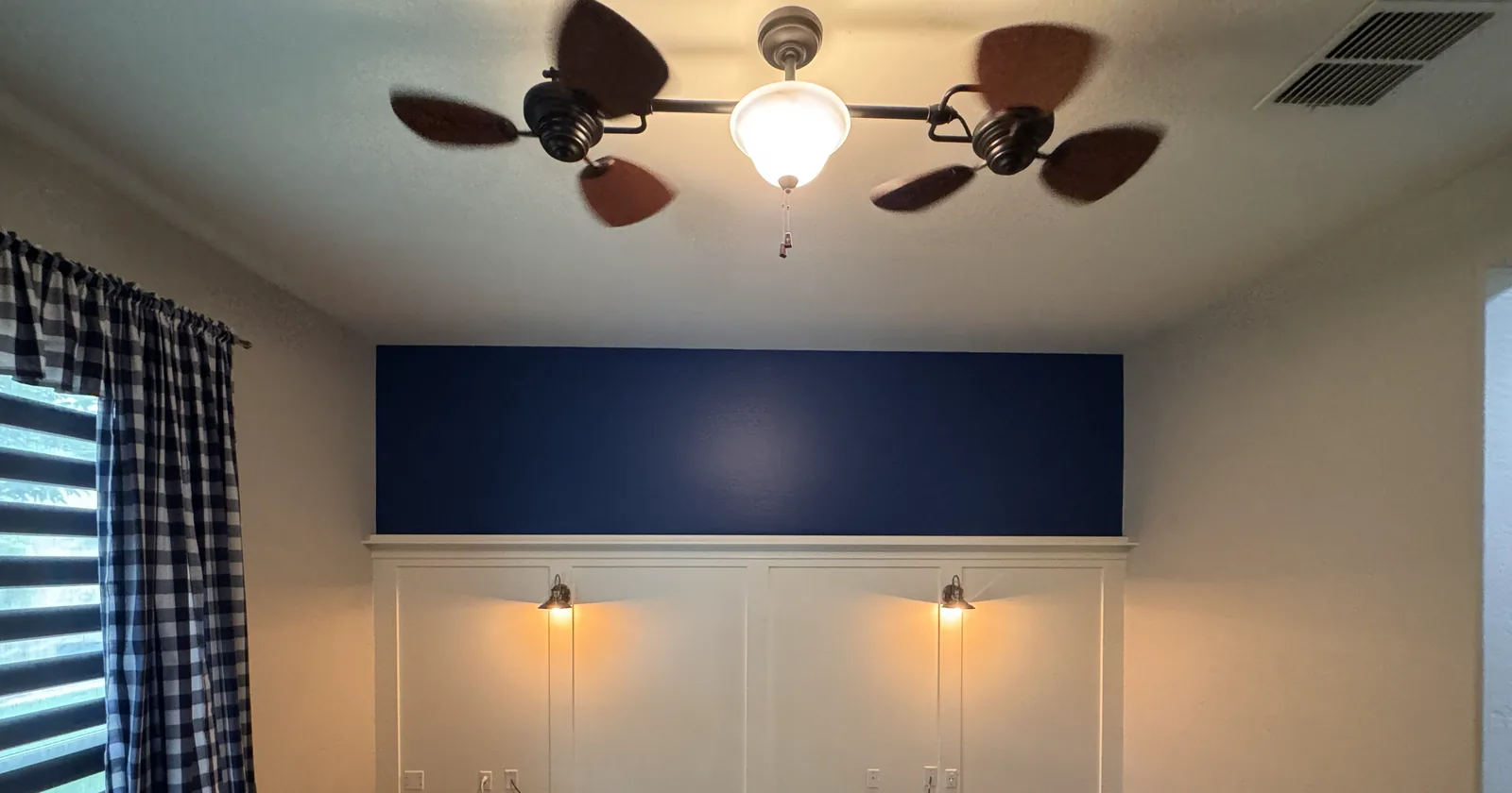A bedroom with a deep navy accent wall above crisp white board-and-batten wainscoting — interior work by Valley Painting Pros.