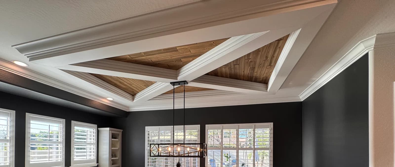 A coffered dining-room ceiling with a natural-wood inlay and crisp white beams above deep charcoal walls — interior painting by Valley Painting Pros in the East Valley.