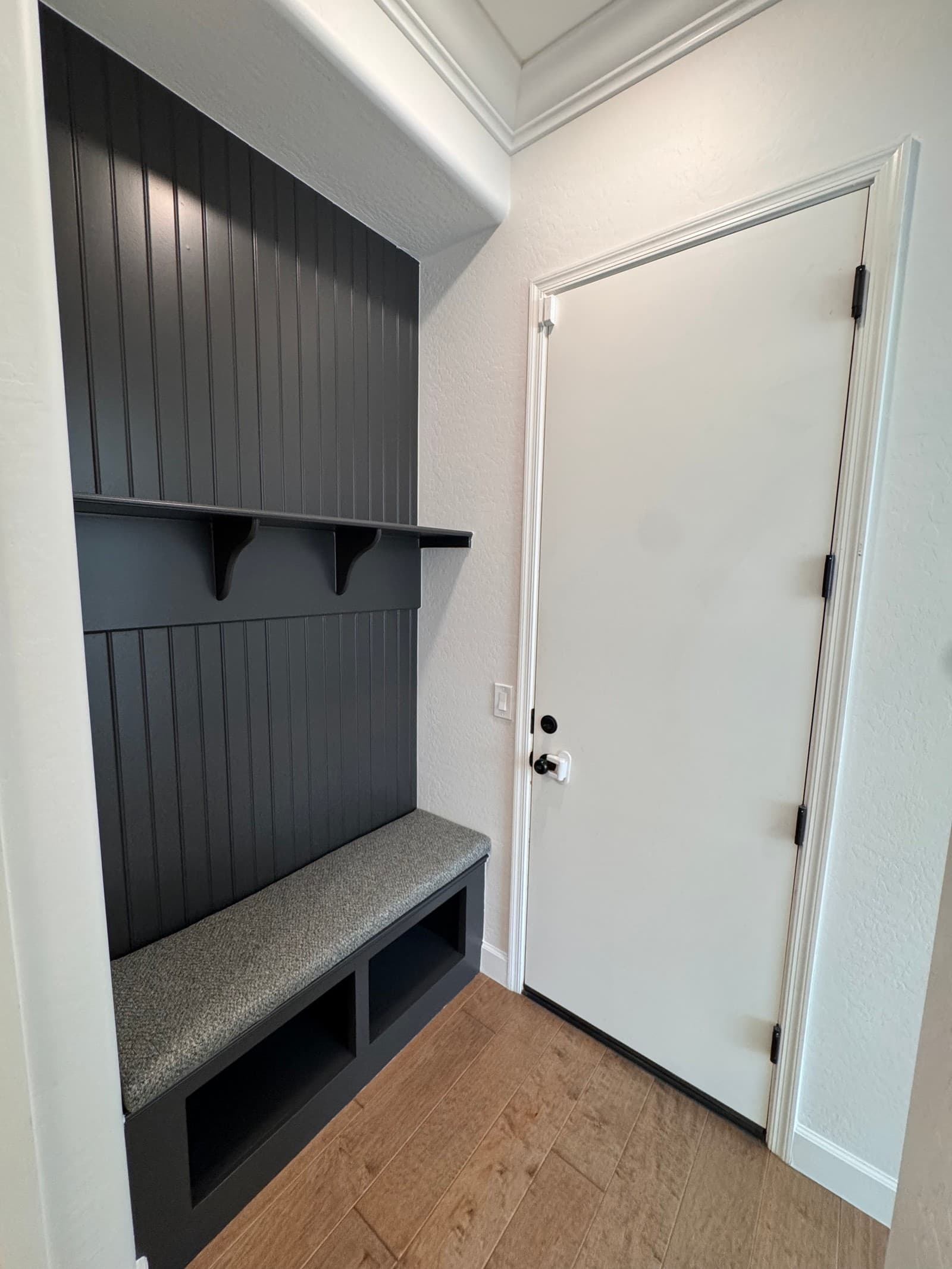 A custom mudroom bench and built-in finished in deep charcoal beside a white interior door — interior work by Valley Painting Pros.