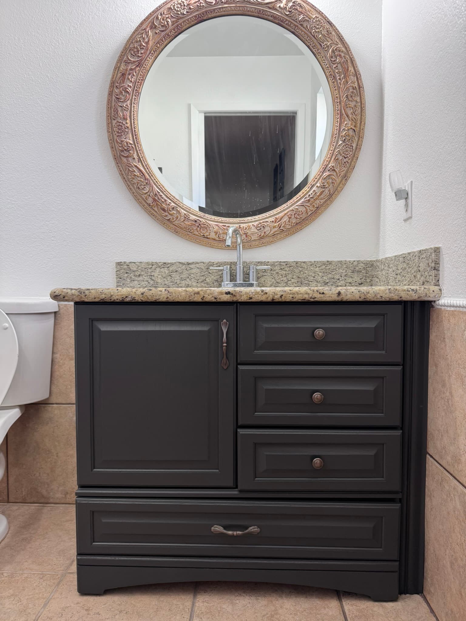 Dark refinished bathroom vanity with framed mirror and granite counter