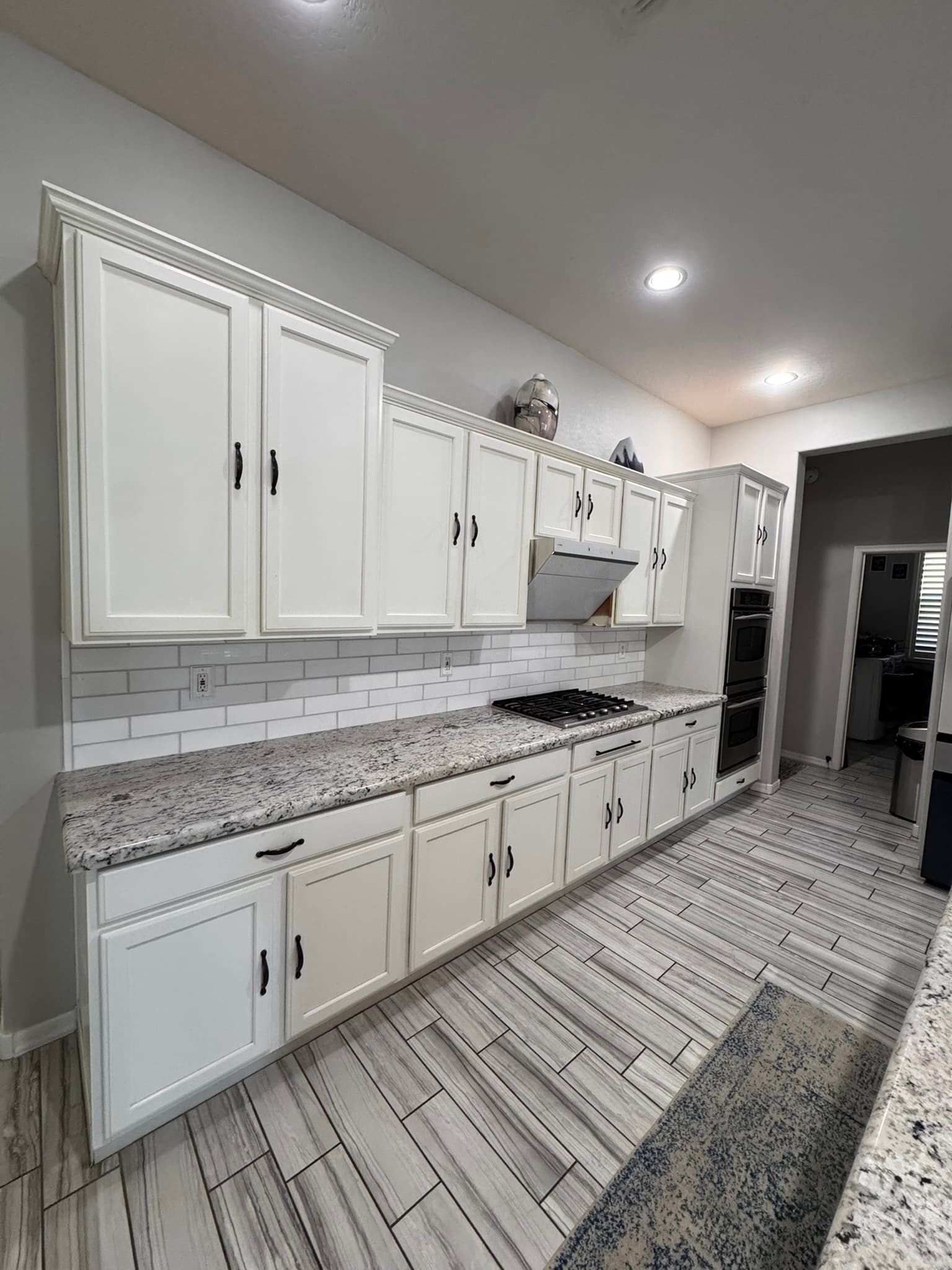Long kitchen wall with refinished white cabinets and black pulls